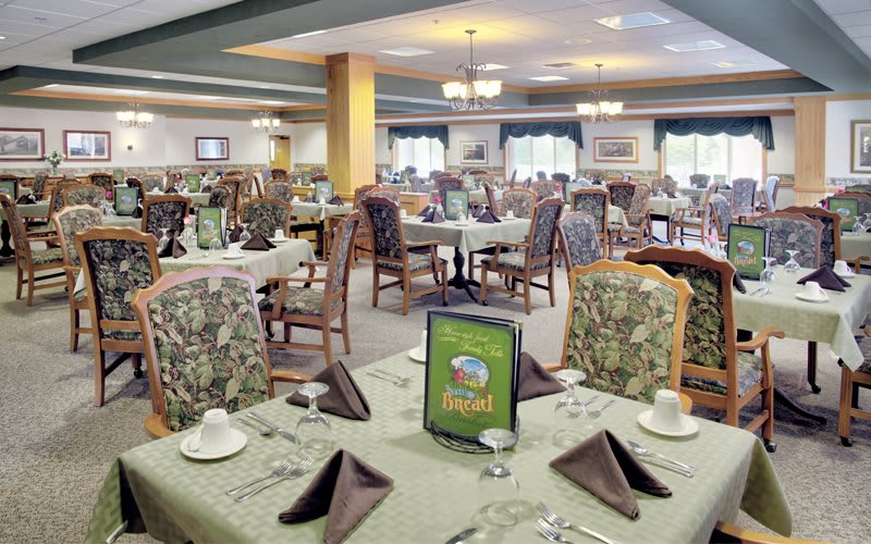An elegant dining room with neatly arranged tables and chairs, featuring place settings and decorative napkins.