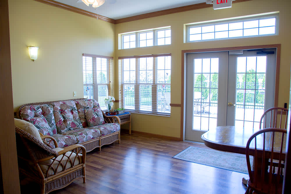 A bright and airy living room with large windows and a floral-patterned sofa.