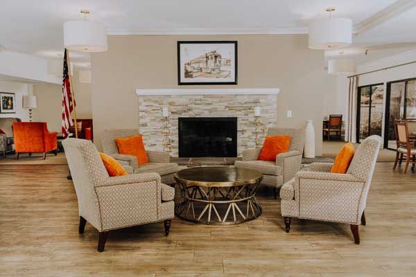 A cozy living room with a fireplace surrounded by four armchairs and a decorative coffee table.