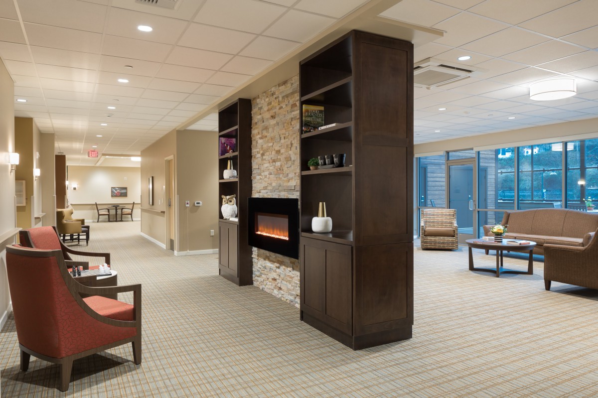 A modern living room featuring a fireplace flanked by tall, dark wooden shelves and contemporary seating.