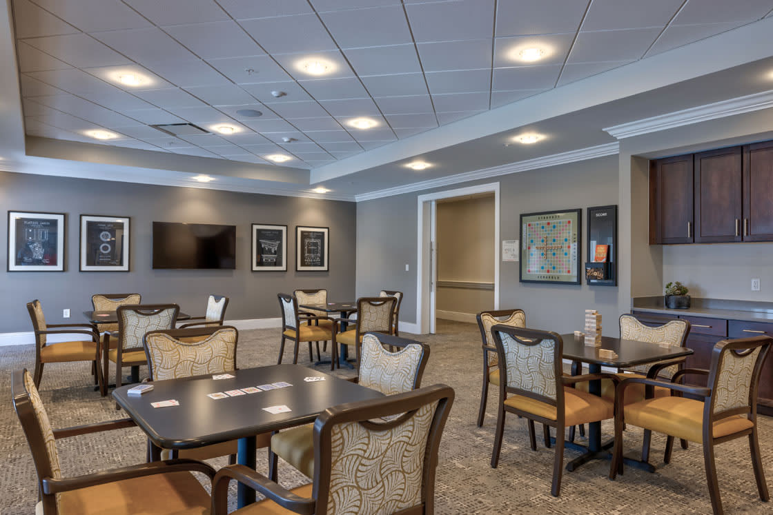 A modern dining area with tables and chairs, featuring a clean interior design and ceiling lights.