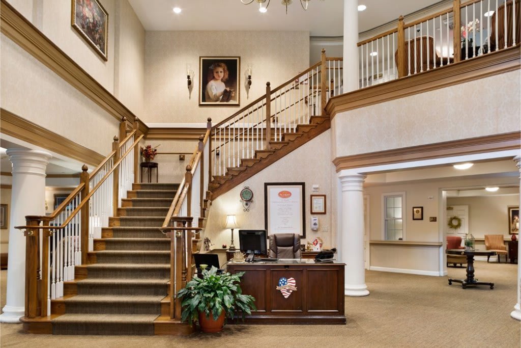 A spacious office interior featuring a grand staircase, a reception desk, and elegant decor.