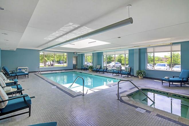 A bright indoor swimming pool and hot tub area with large windows.