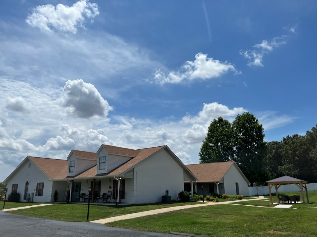 A row of suburban houses under a blue sky with scattered clouds.