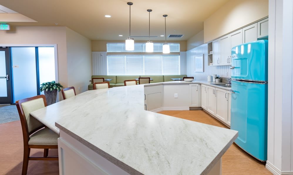 A modern kitchen with a large marble countertop and pendant lighting.