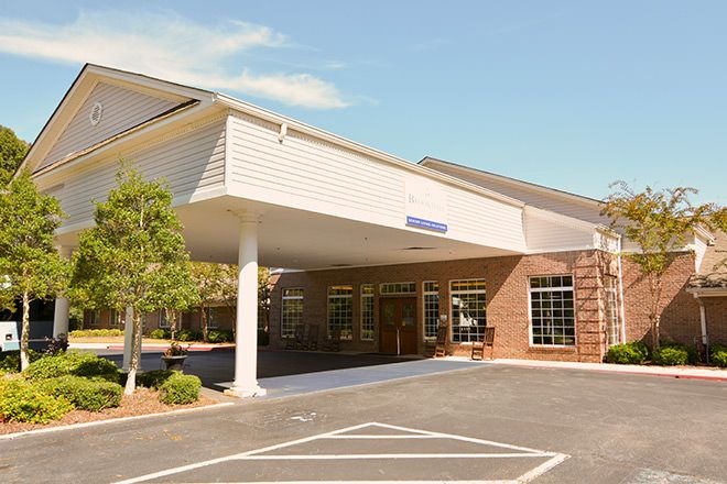 A building with a covered entrance and adjacent parking lot.