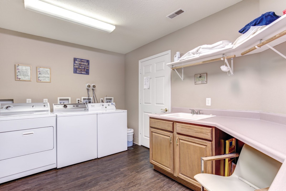 A neat and organized laundry room with a washer, dryer, sink, and ample countertop space.