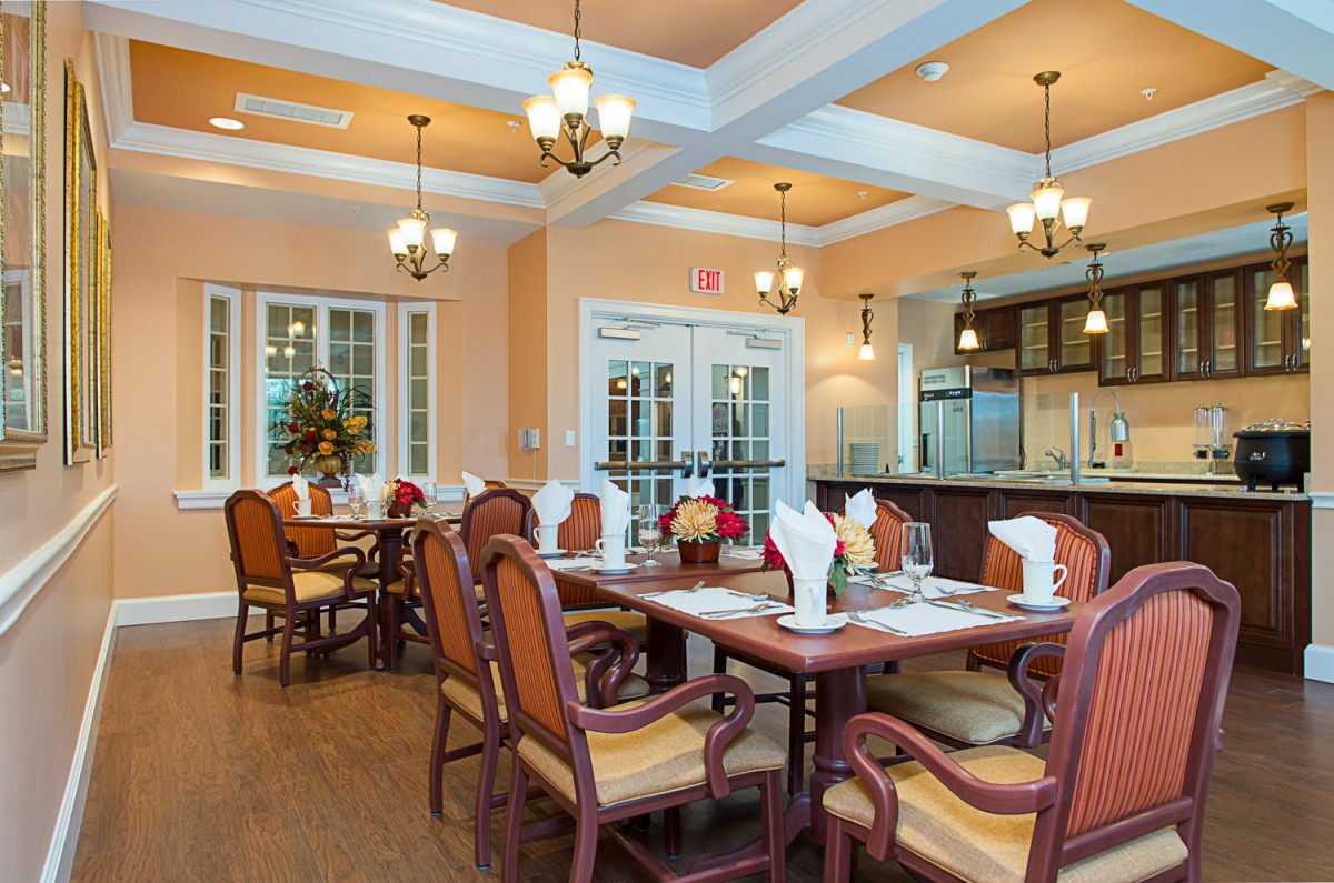 An elegantly decorated dining room with wooden tables and chairs set for a meal, featuring warm lighting and tasteful decor.