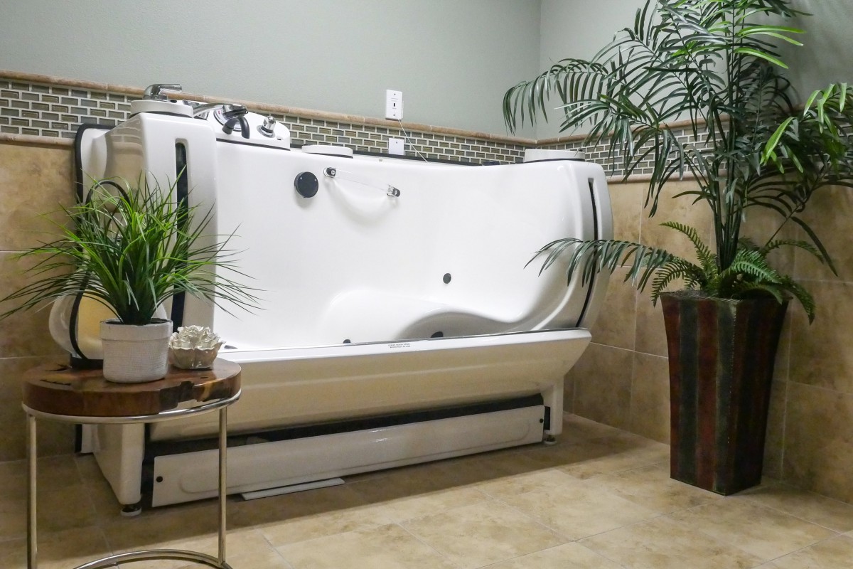 A modern bathroom featuring a walk-in bathtub surrounded by indoor plants.