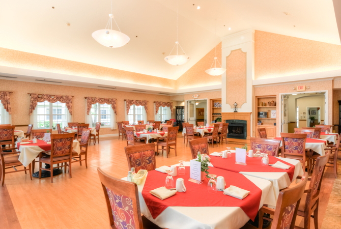 A warm and inviting restaurant dining room with neatly arranged tables and red tablecloths.