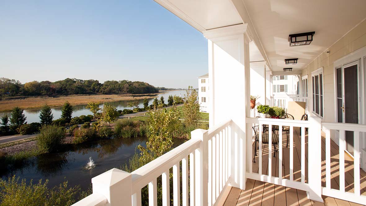 A sunny view from a balcony overlooking a river and lush green landscape.