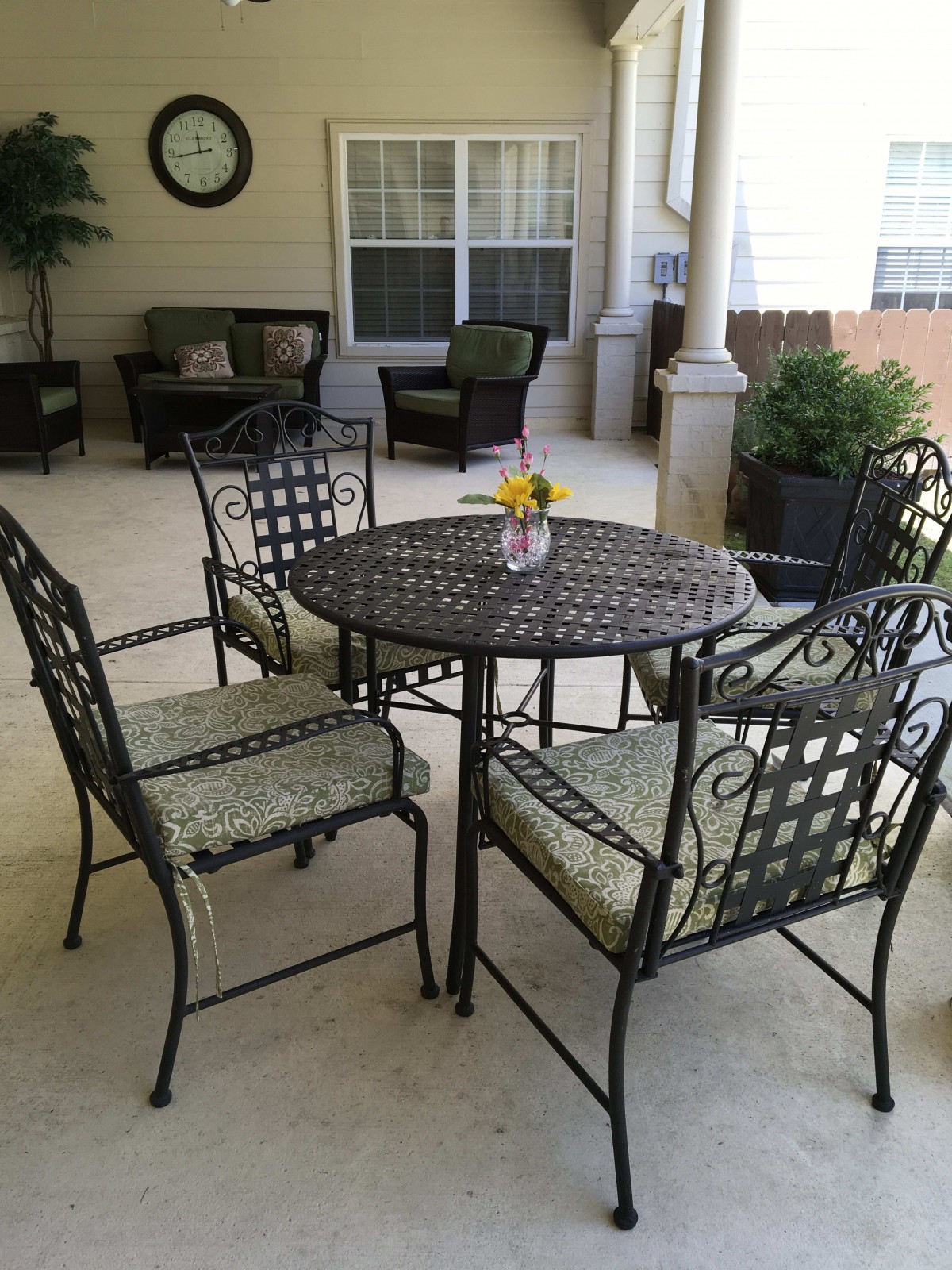 A cozy patio setup featuring an iron table and chairs, perfect for outdoor seating.