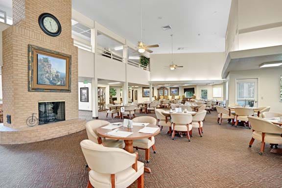 A spacious and modern dining area with neutral decor, featuring tables and chairs.