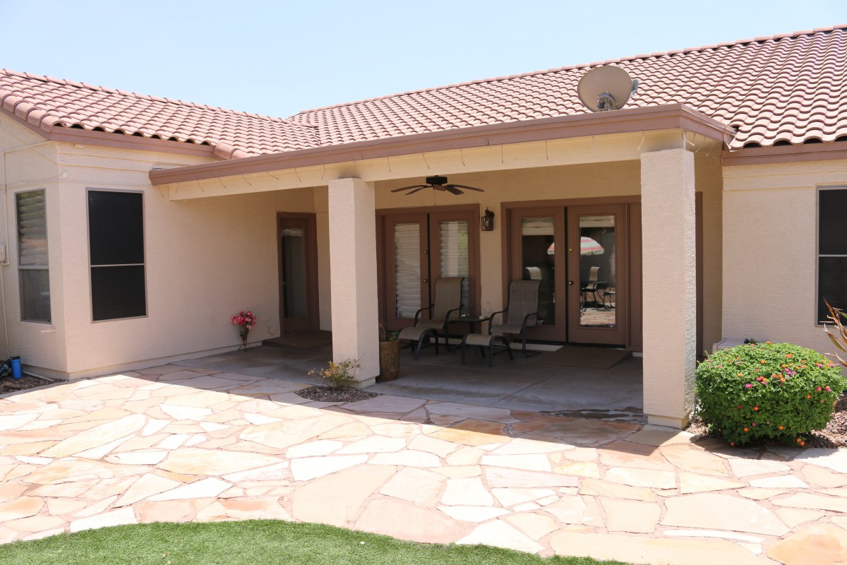 A residential patio area with outdoor seating and tiled flooring under a covered structure.