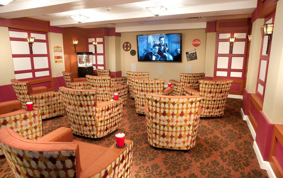 A cozy lounge area with patterned chairs facing a large television.