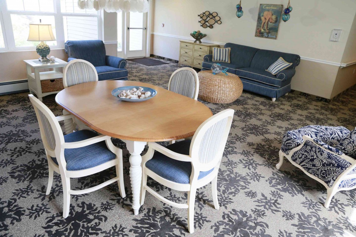 A cozy living and dining area featuring a wooden table with chairs, a blue sofa, and a patterned rug.