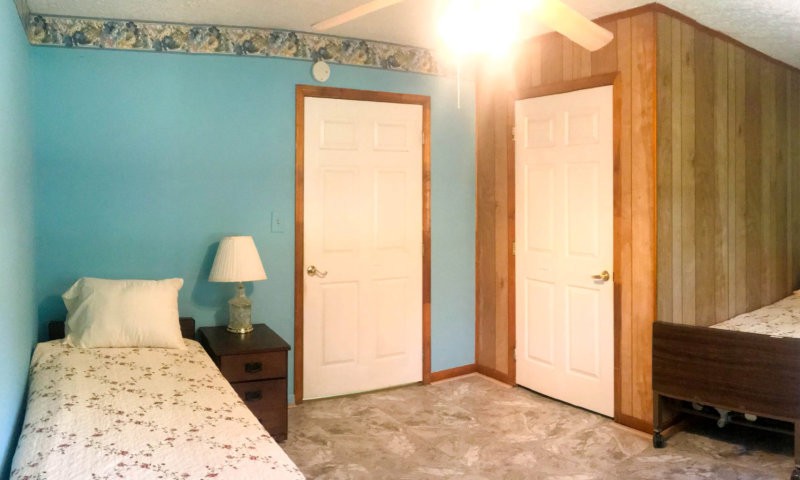 A cozy bedroom with a blue accent wall, featuring two white doors and a bedside table with a lamp.