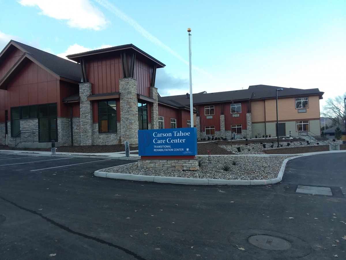 Entrance view of a modern library with a sign and parking area.