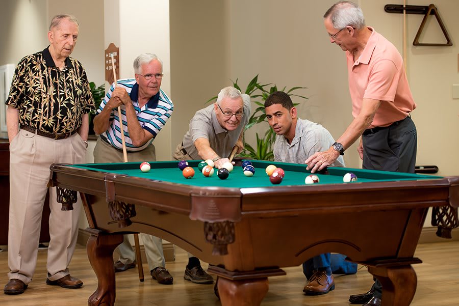A group of men playing billiards together indoors.