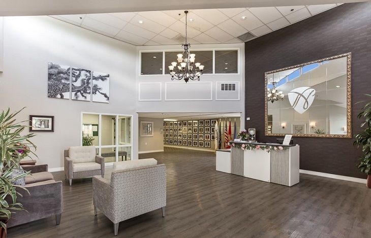 A spacious and modern lobby with a chandelier, reception desk, and comfortable seating.