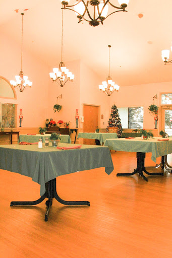 A cozy dining area featuring neatly arranged tables, elegant chandeliers, and festive decorations.