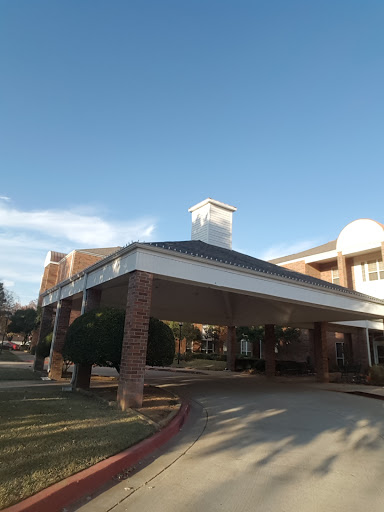 A welcoming entrance to a residential facility with a classic architectural design under a clear blue sky.