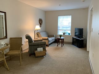 A cozy living room with a sofa, armchair, and a television.
