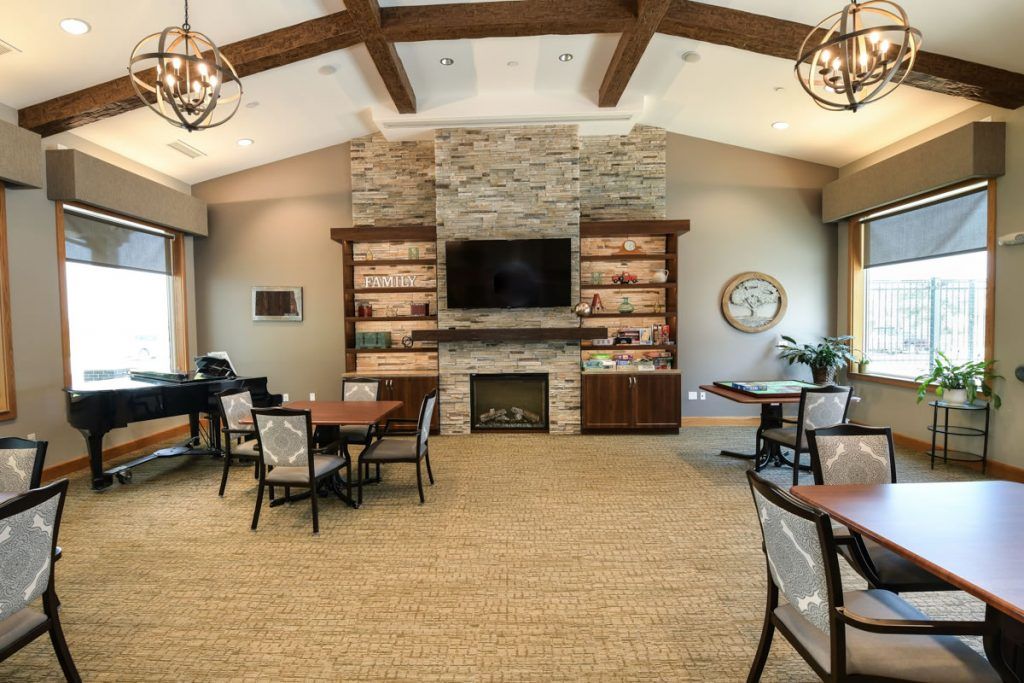 A cozy living room with a stone fireplace and modern decor, featuring wooden beams, chandeliers, and multiple seating areas.