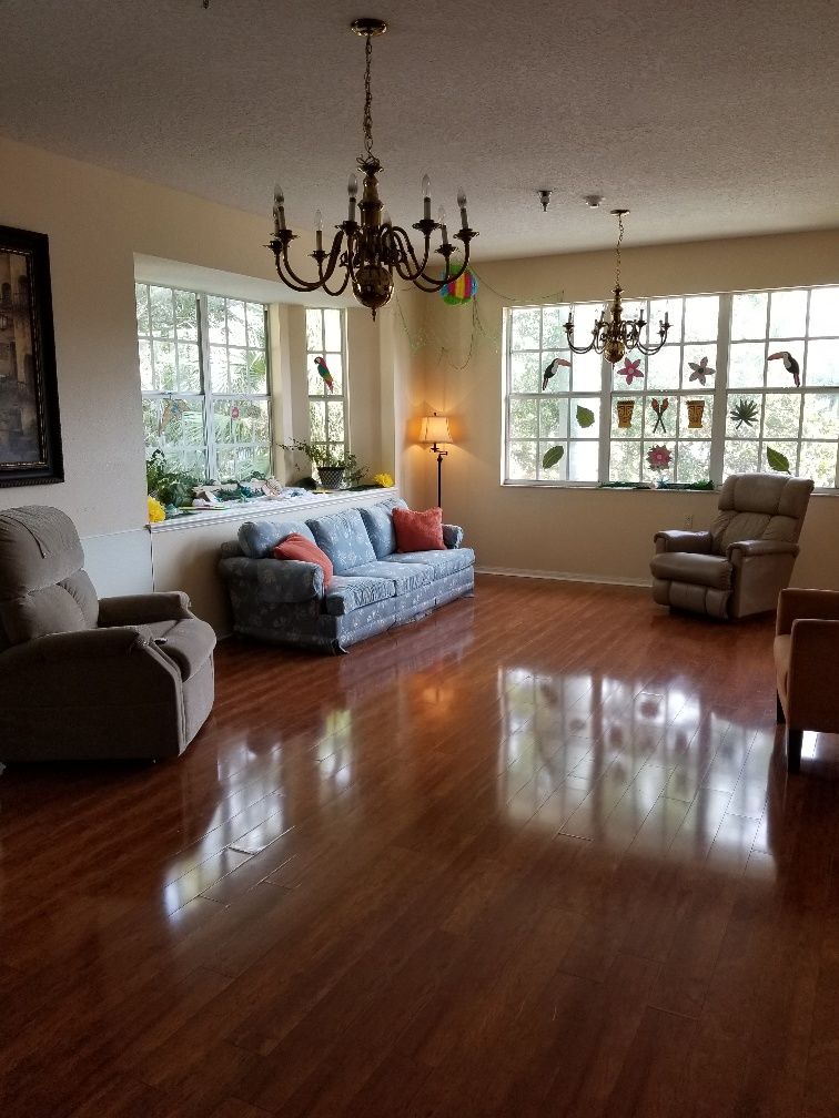 A cozy living room with a sofa, armchairs, and natural light streaming through large windows.