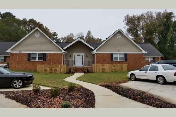 A suburban brick house with a lawn and driveway.