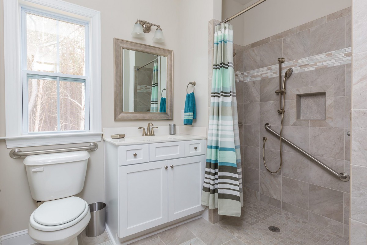 A modern bathroom with a shower area, vanity, and striped shower curtain.
