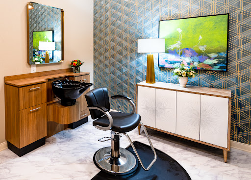 A stylish and modern hair salon interior featuring a sleek barber chair, wash station, and contemporary decor.