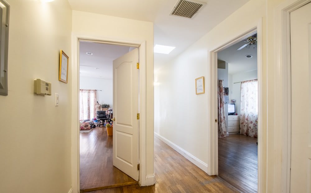 A bright hallway with wooden flooring and open doors leading to other rooms.