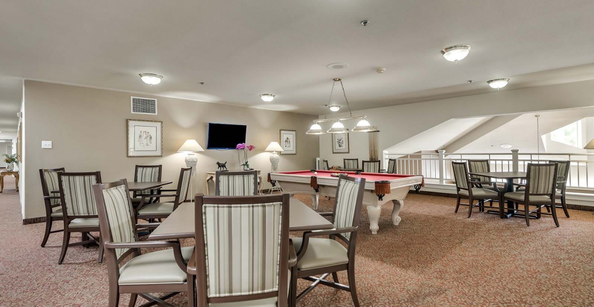 A well-lit game room featuring pool tables, a television, and comfortable seating.