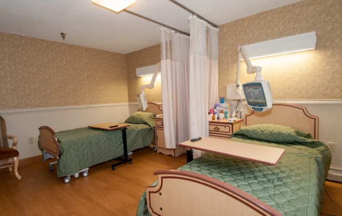 A hospital room with two patient beds and medical equipment.