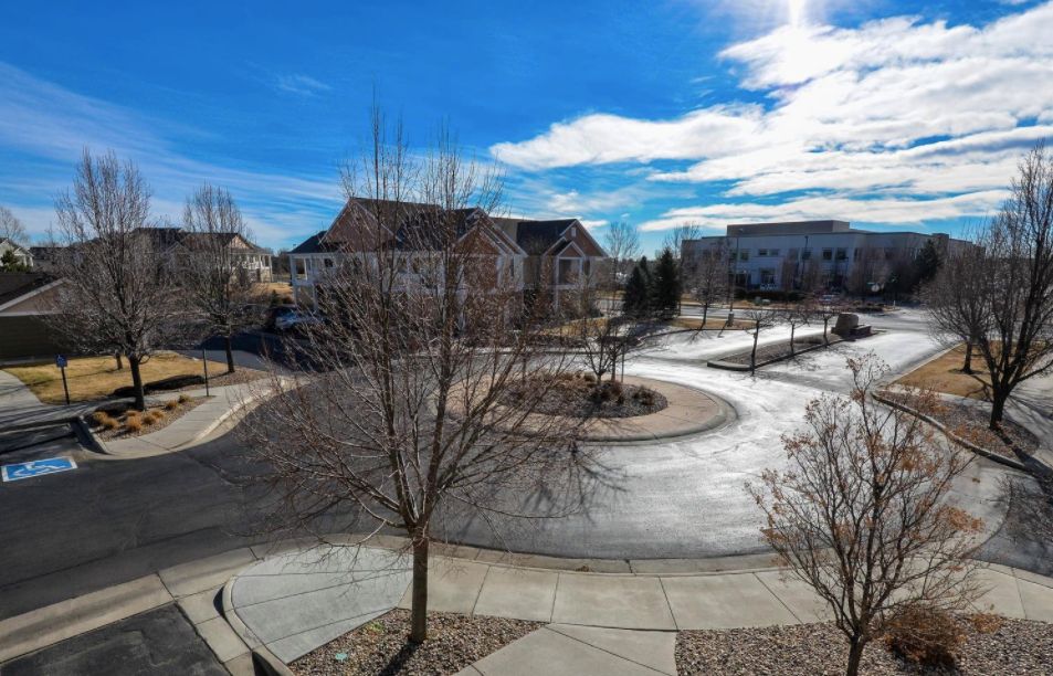 A quiet neighborhood with houses lining the curved street under a blue sky.