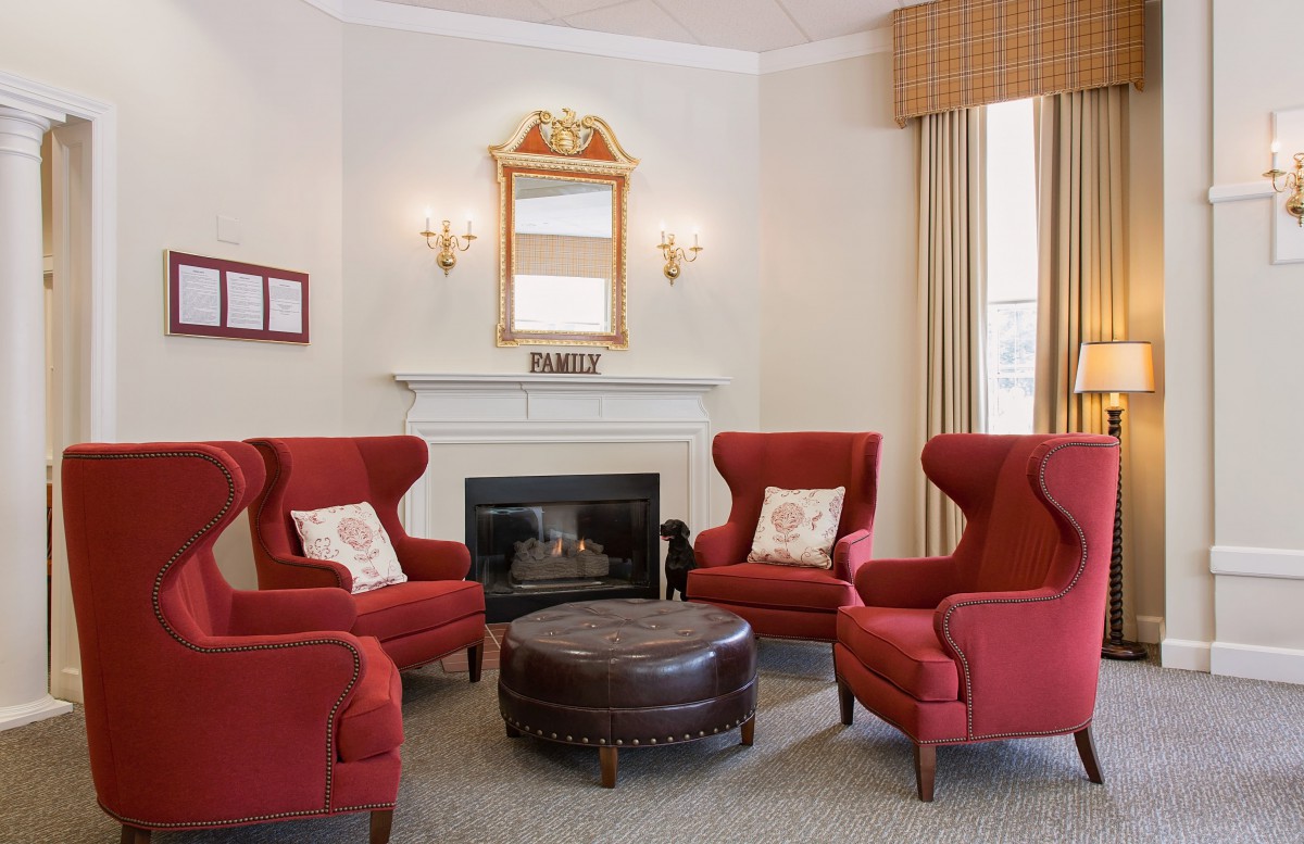 A cozy living room featuring red armchairs, a fireplace, and a decorative mirror.