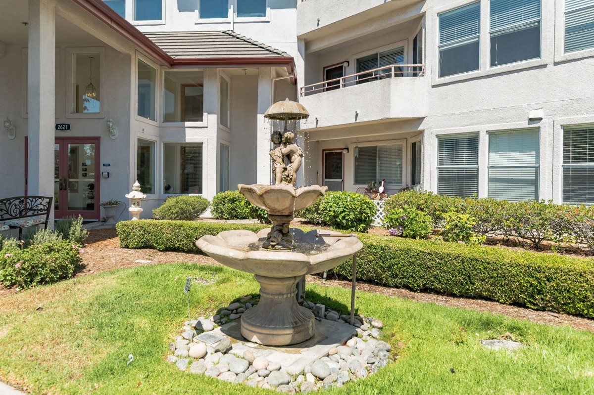 A decorative fountain in a building courtyard surrounded by landscaping.