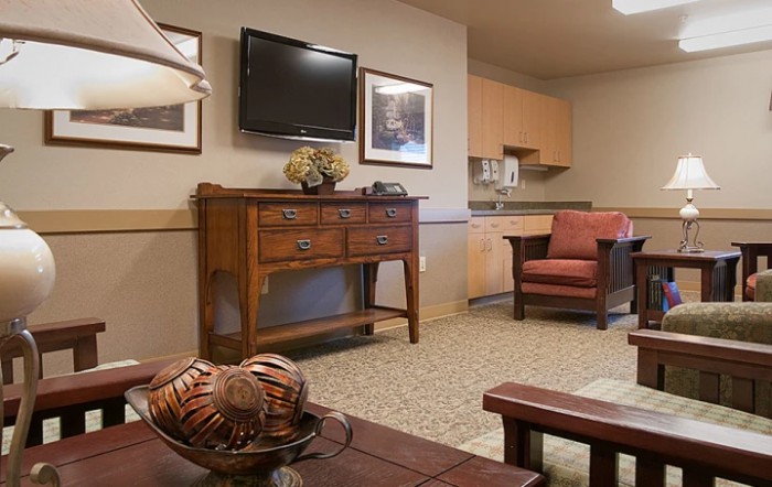 A cozy living room with a television, armchair, and wooden cabinet.