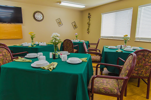 A cozy dining area set with green tablecloths and floral decorations.
