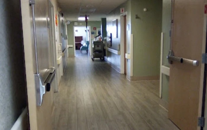 A view of a hospital corridor with medical equipment and rooms along the sides.