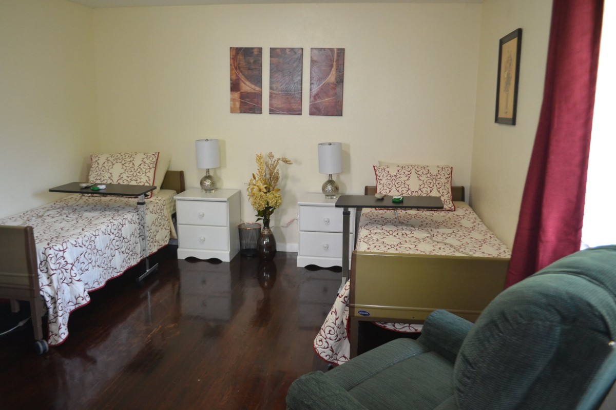 A cozy bedroom with two beds, nightstands, lamps, and artwork on the wall.