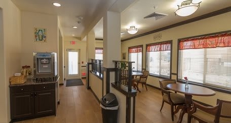 A cozy interior hallway with tables and chairs by the windows.
