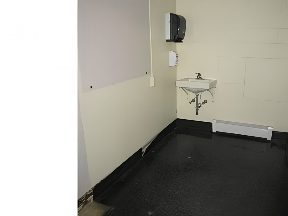 A small bathroom corner with a sink and wall-mounted dispenser.