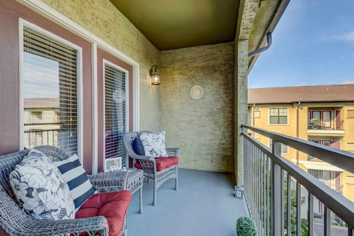 A cozy balcony with cushioned chairs and a view of the surrounding buildings.