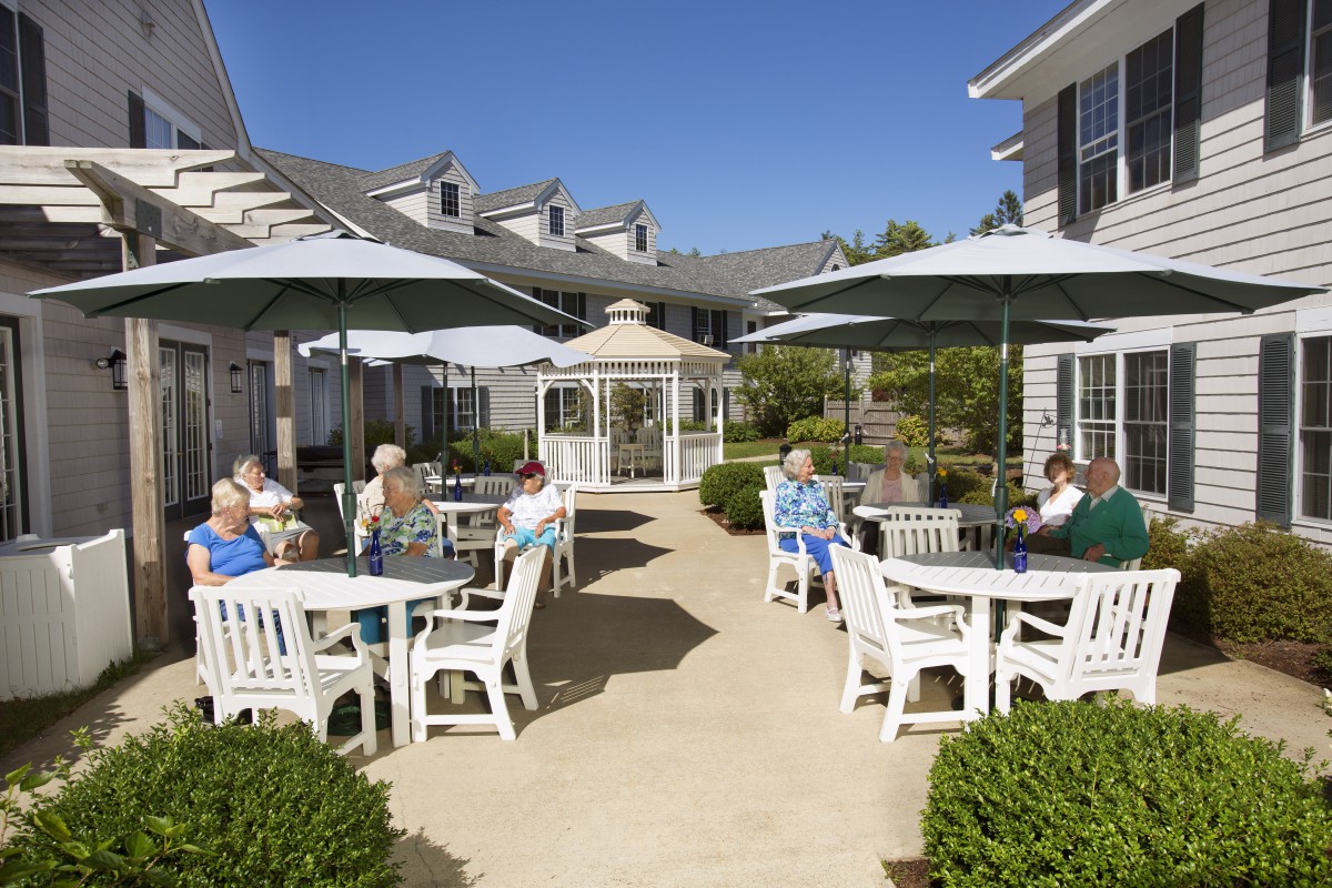 Seniors enjoying a sunny day on the patio of a retirement home.