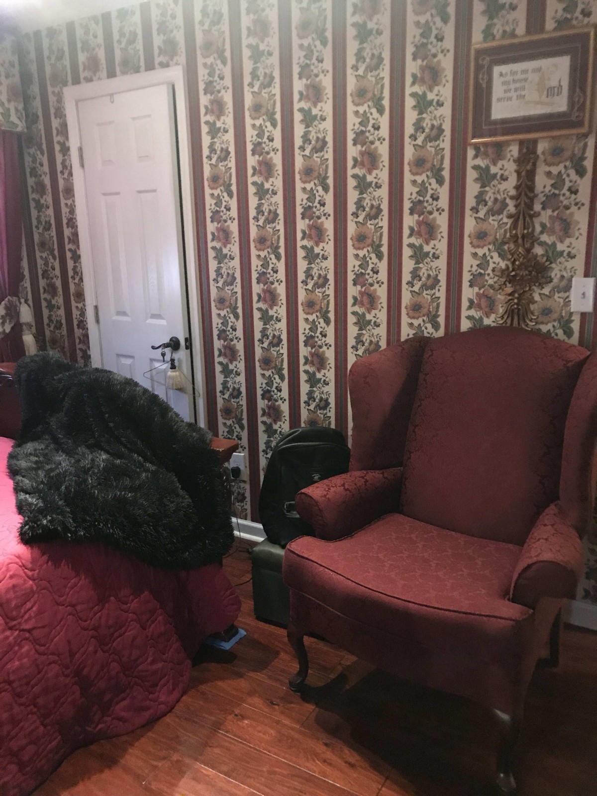A vintage-style bedroom with floral wallpaper and an armchair.
