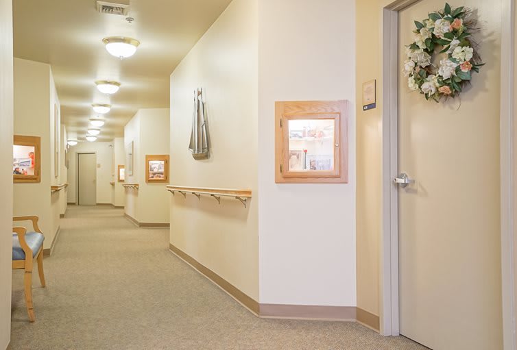 A well-lit hallway with doors and framed decorations on the walls.
