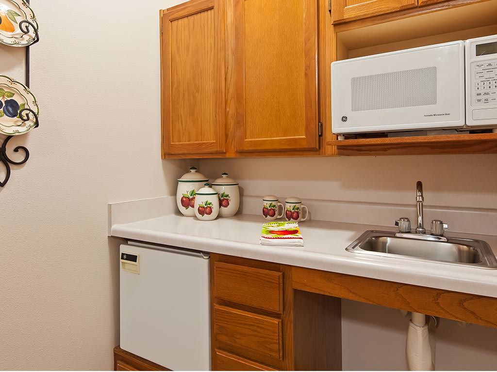 A compact kitchen with wooden cabinets, a microwave, and a small sink.