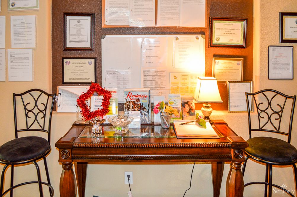A neatly organized office desk adorned with certificates, awards, and a small lamp.